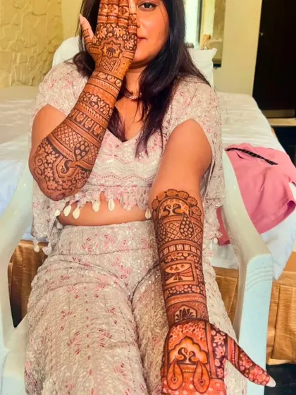 A stylish pose from a happy client, showing off her full-arm mehndi with personalized initials.