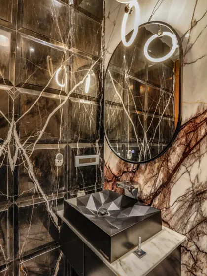 In this powder room, we used dramatic, book-matched marble and beveled wall tiles to create an immersive experience. The geometric basin and modern lighting add a contemporary edge, proving that even small spaces can make a powerful statement.