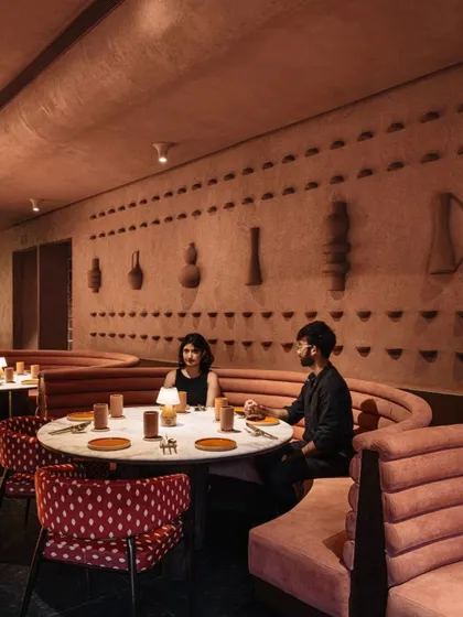 Curved banquette seating and custom terracotta wall art create an intimate dining nook at Idylll. The entire space is a testament to the power of tactile materials in shaping atmosphere.
