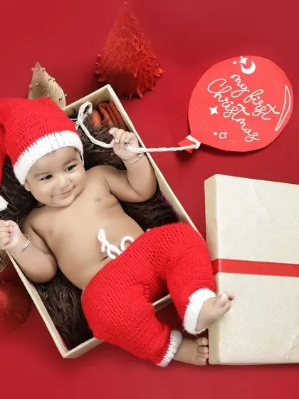 A creative flat-lay style Christmas photo. This newborn is presented as the most precious gift of the season, holding a "My First Christmas" balloon.
