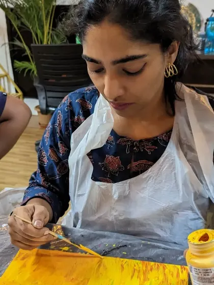A participant focused on her abstract painting, using a palette knife to create interesting textures.