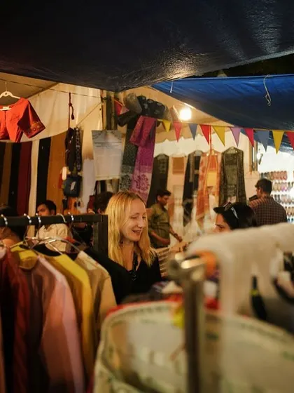 A shopper browses through a rack of handmade apparel. Our markets offer a chance to find unique clothing directly from the creators.