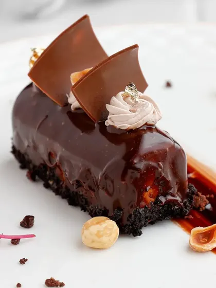 A perfect shot of our Ferrero Rocher Entremet, highlighting the textures from the crunchy base to the smooth ganache and light mousse topping.