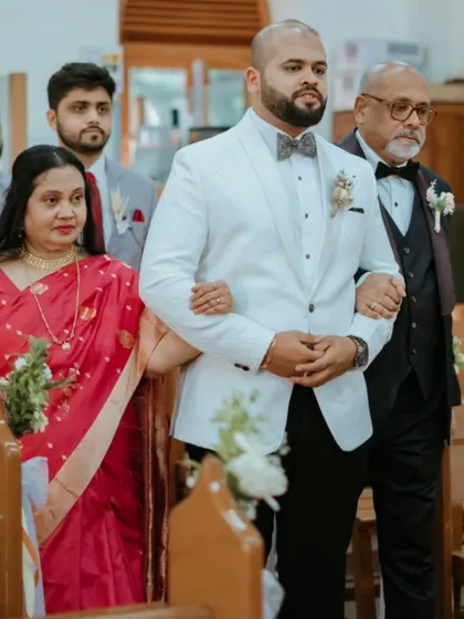 The groom's proud walk down the aisle with his parents, a significant moment at the start of the Catholic wedding ceremony.
