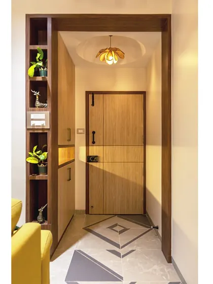 The entryway to this home features custom flooring, a sleek shoe cabinet with integrated shelving for decor, and a warm, welcoming ambiance.
