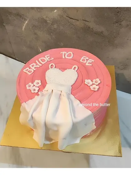A fun and feminine "Bride to be" cake. This pink cake is decorated with a fondant dress, celebrating the bride's journey to her big day.