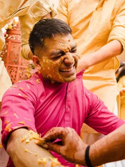The groom's face shows the "pain" of getting haldi applied, a classic and funny moment from the ceremony. His exaggerated expression adds a touch of humor to the album.