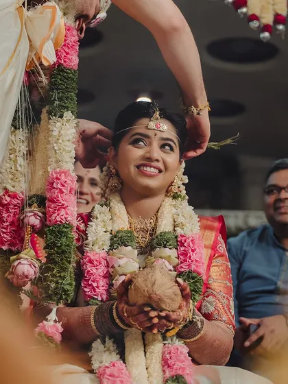A beautiful candid of bride Sahana during her wedding rituals. Her makeup is soft and natural, allowing her joyful expressions to be the main focus.