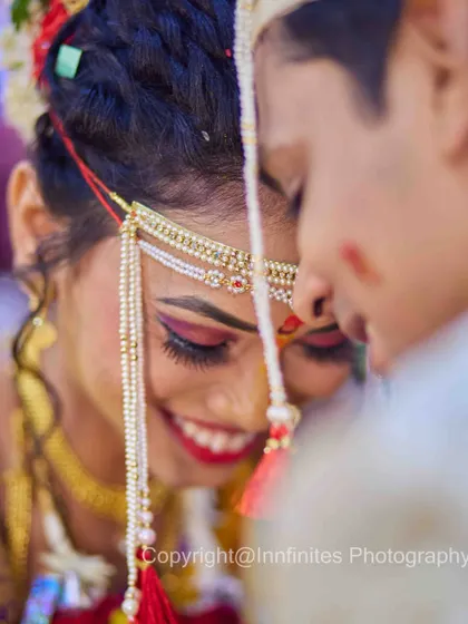 A joyful, tight close-up that feels personal and warm. The bride's bright smile and the traditional Mundavalya are the focus of this happy moment.