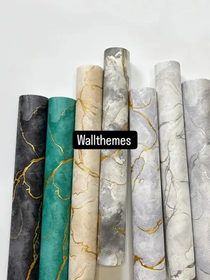 A collection of wallpaper rolls with a natural marble vein pattern in various colors like black, teal, beige, and grey.