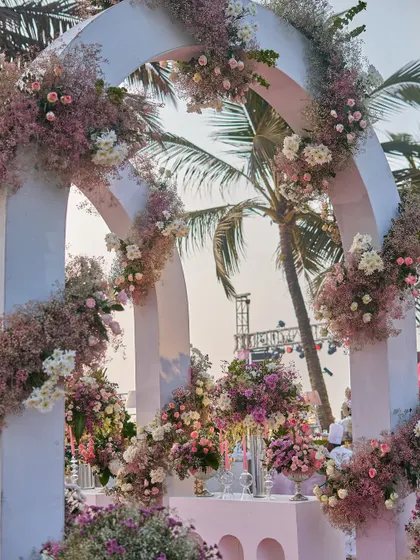 The floral-adorned arches of the entranceway, with palm trees peeking through. This shows how I integrate the natural surroundings into my destination wedding designs.