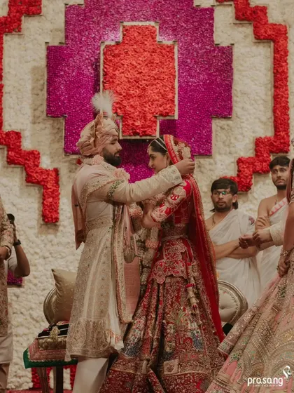 The groom lovingly places the sindoor, a pivotal moment in the ceremony. The backdrop of intricate floral art frames this intimate ritual beautifully.