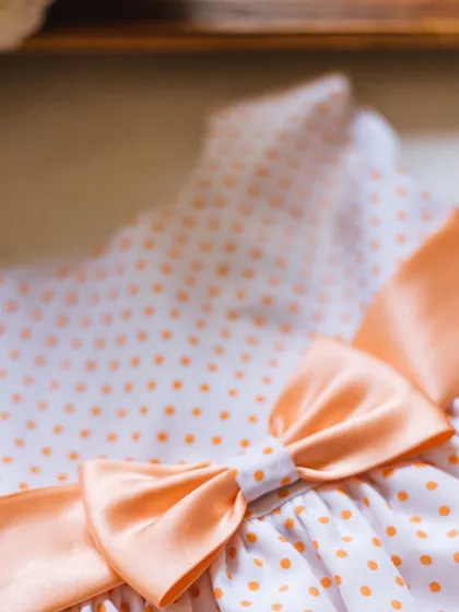 A closer look at the peach polka dot dress, focusing on the perfectly tied satin bow that serves as the centerpiece.