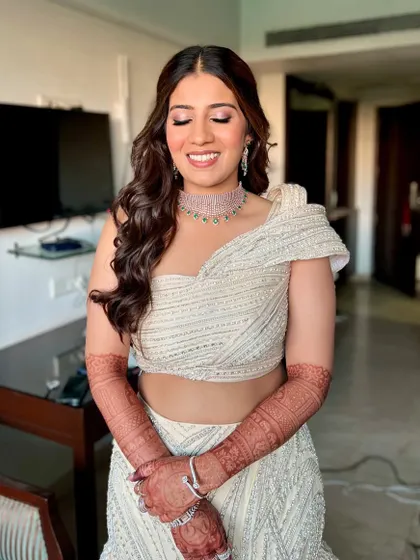 The complete sangeet look, with a stunning white lehenga and sparkling diamond jewellery. The soft waves in her hair and the radiant makeup create a sophisticated and glamorous style.