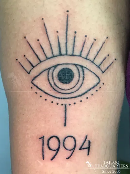 A stylized all-seeing eye tattoo with the year "1994" underneath, a personal and symbolic design.