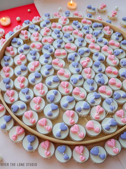 A tray filled with dozens of hand-poured heart tealight candles in pink and purple. This shows the scale of a bulk order for a birthday party, with each candle made with care.