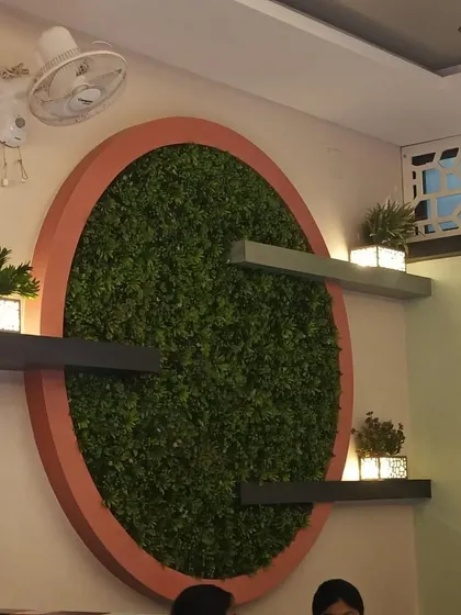 A view of the circular green wall art installation in a cafe or home setting. It serves as a creative and eye-catching decor element that requires zero care.
