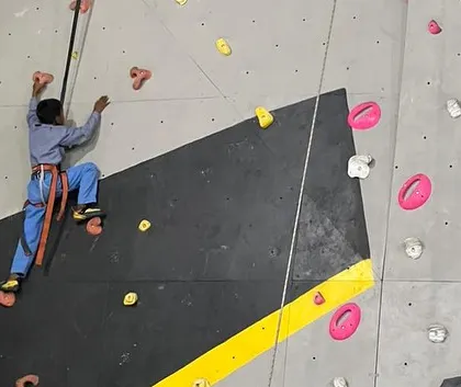 A young climber in a harness confidently makes his way up the top-rope wall during our community outreach event. We provide all the gear and guidance to ensure a safe and empowering first climb.