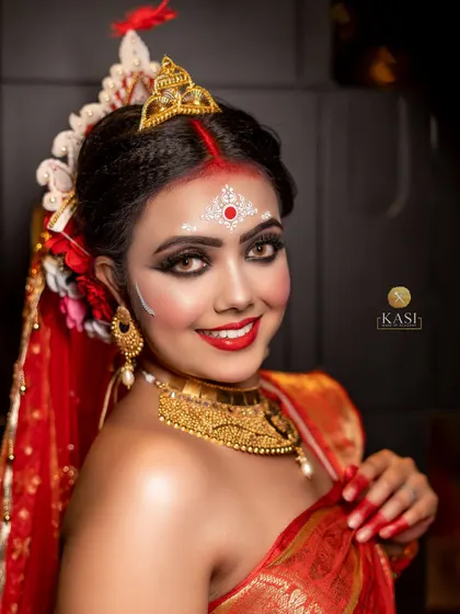 This portrait captures the beautiful smile of a Bengali bride. The makeup is designed to enhance her features while staying true to the traditional aesthetic.