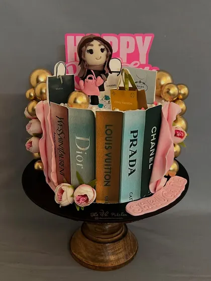 For the ultimate fashion lover, this cake features edible shopping bags from brands like Dior and Louis Vuitton, all propped against edible books. The shopaholic figure on top is also handmade.