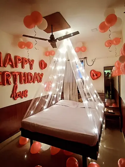 A classic red and white themed birthday room decoration. This setup includes "Happy Birthday love" foil balloons on the wall and a light-up canopy over the bed for a cozy and celebratory feel.