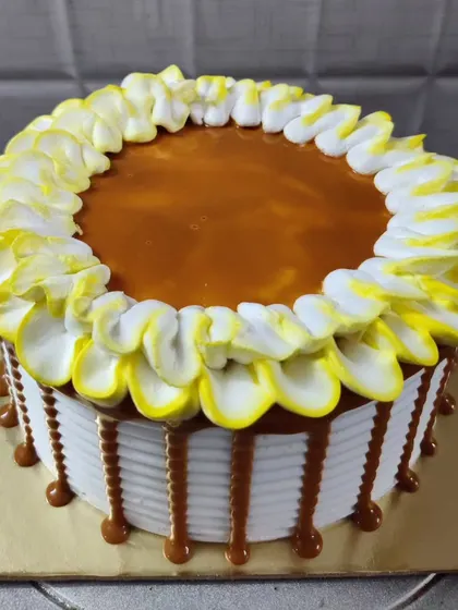 A butterscotch drip cake with a beautiful petal-style piping on top. The combination of sweet and crunchy is always a hit.