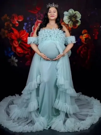 A client looking regal with a crown and our light blue ruffled gown. This dress is perfect for creating a queenly, celebratory look for your maternity photos.