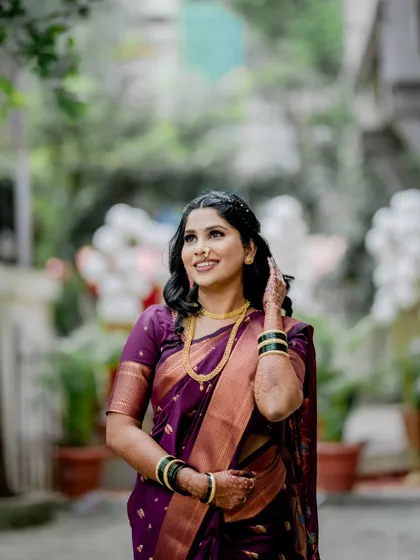 A stunning outdoor portrait of the bride in a deep purple traditional saree. The natural light and background beautifully complement her elegant and classic look.