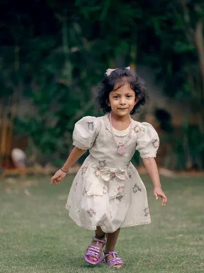 A sweet, candid shot of a little girl walking in a garden, capturing her natural curiosity and movement.