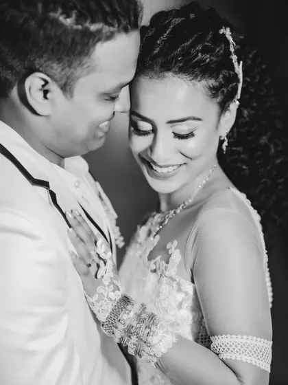 A happy and intimate black and white portrait of the couple. The monochrome format emphasizes their bright smiles and the texture of the bride's dress.