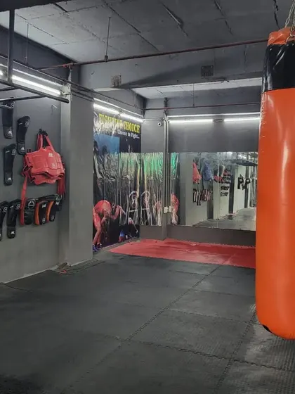 The "Fighting Choice" heavy bag, a core piece of equipment for our striking training. Behind it, you can see our wall-mounted gear storage, keeping the gym organized and professional.