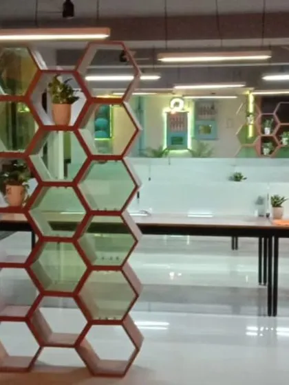 This hexagonal wood and glass partition was designed for a modern office to create a semi-private meeting area. It adds a biophilic touch with integrated planters while maintaining an open, airy feel.