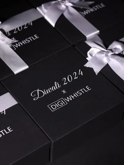 A stack of custom-branded Diwali gift boxes for DIGIWHISTLE, tied with elegant white ribbons, ready for dispatch.