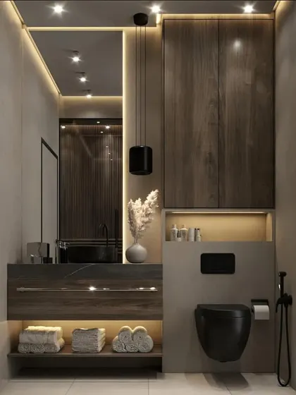 A sophisticated bathroom with dark wood cabinetry and marble-like countertops. The black fixtures and toilet, along with the warm under-cabinet lighting, create a dramatic and high-end feel.