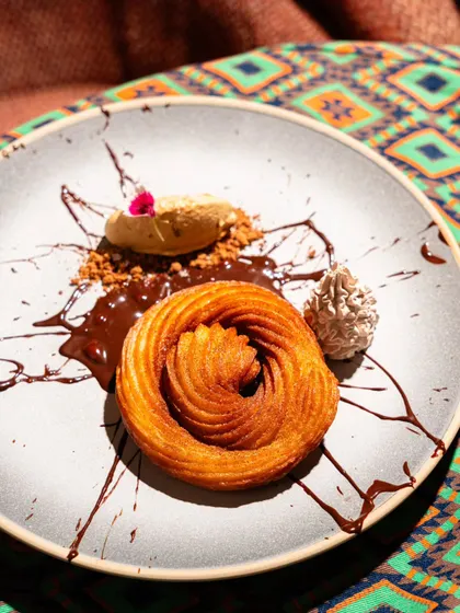 A beautifully plated spiral churro with chocolate sauce and ice cream at Lyla Bombay. This dessert shot is composed to look like a piece of modern art.