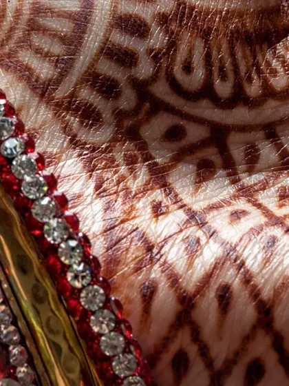 A close-up of intricate bridal mehendi. We believe in celebrating every tradition, and the beautiful art of henna is a key part of the Indian wedding experience.