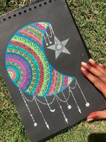 A crescent moon filled with a spectrum of colorful mandala patterns and adorned with dangling stars. This piece captures the magic of the night sky.