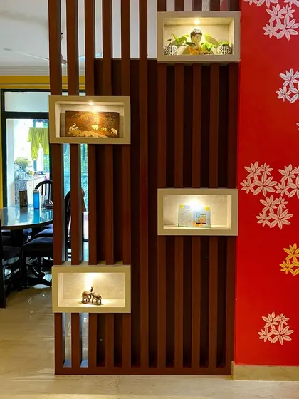 A creative partition design using wooden slats and illuminated display boxes, separating the dining area from the living room while adding an artistic touch.