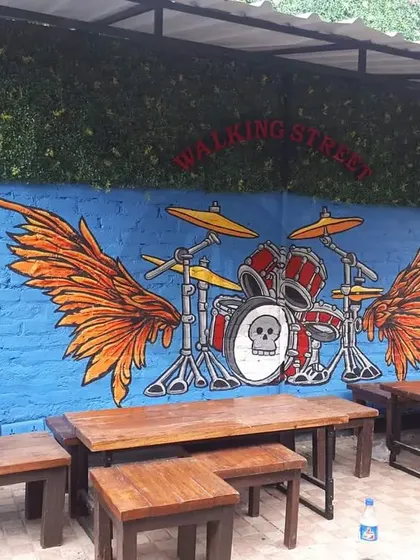 This mural for Walking Street in Gurgaon features a drum set with fiery wings, capturing the musical and high-energy vibe of the venue. It's a perfect backdrop for a live music or bar area.
