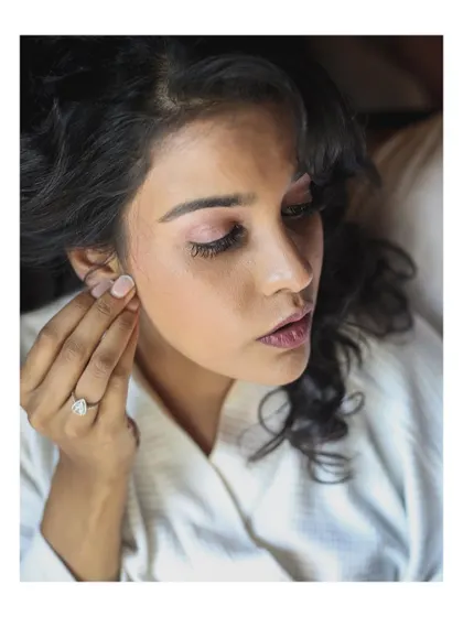 A close-up of the bride putting on her earring, a delicate getting-ready moment.