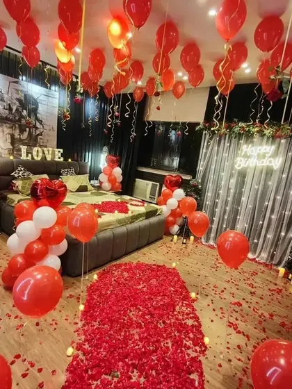 We transform any room into a romantic paradise. This birthday surprise features a dramatic rose petal walkway, hundreds of red and white balloons, and a glowing neon sign, creating an unforgettable grand gesture.