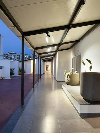 The terrace corridor at the Land Capital Primero project. The design uses a simple, robust steel structure and large planters to create a functional and aesthetically pleasing outdoor passage.