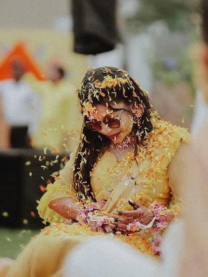 A candid shot of the bride being showered with flower petals during a joyous moment of the Haldi ceremony.
