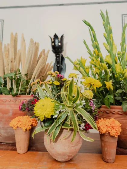 A close-up of the floral arrangements, showing a mix of yellow chrysanthemums, marigolds, and other wildflowers in traditional terracotta pots.