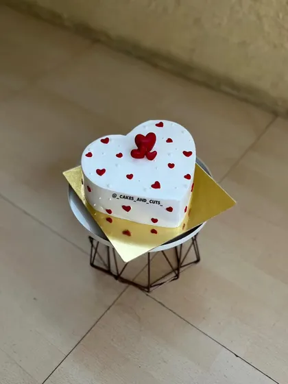A heart-shaped cake decorated with small red hearts, a classic choice for a romantic celebration.