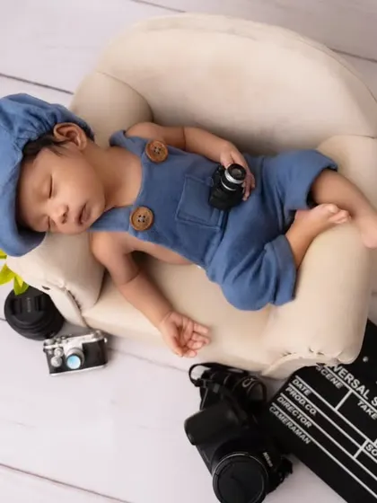 An aerial view of our little director asleep on his mini sofa. This angle showcases the entire creative setup, from the camera props to the clapperboard.
