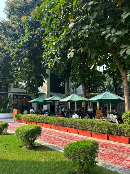 The view of the cafe from the walkway, showing the beautiful landscaping and inviting outdoor seating area.