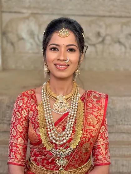 For Lipika, a classic red saree look. The makeup is bold yet elegant, with a skin-like finish and traditional jewelry like the Surya Chandra hairpiece.