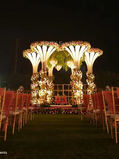 An overview of a grand outdoor wedding mandap at night. The illuminated structures, floral arrangements, and perfectly aligned guest seating demonstrate our ability to transform large lawns into spectacular wedding venues.