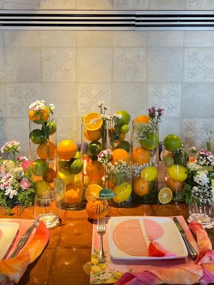 This summer birthday tablescape is bursting with freshness, using tall glass vases filled with whole lemons, limes, and oranges, interspersed with delicate floral bouquets.